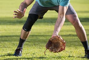 Man playing baseball while wearing Copper Fit® Ice Knee Sleeves
