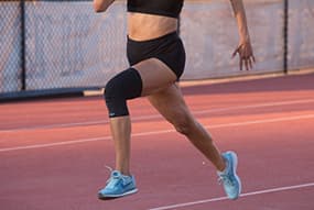 Woman running while wearing Copper Fit® Ice Knee Sleeves